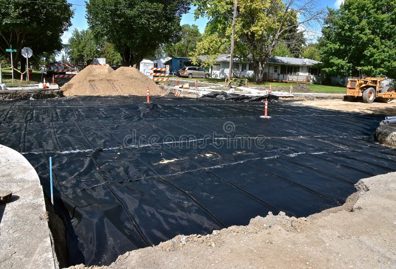 A plastic tarpaulin  forwater-proofing is laid on the ground of a street project which will be buried by soil and concrete. A plastic tarpaulin  forwater-proofing is laid on the ground of a street project which will be buried by soil and concrete.