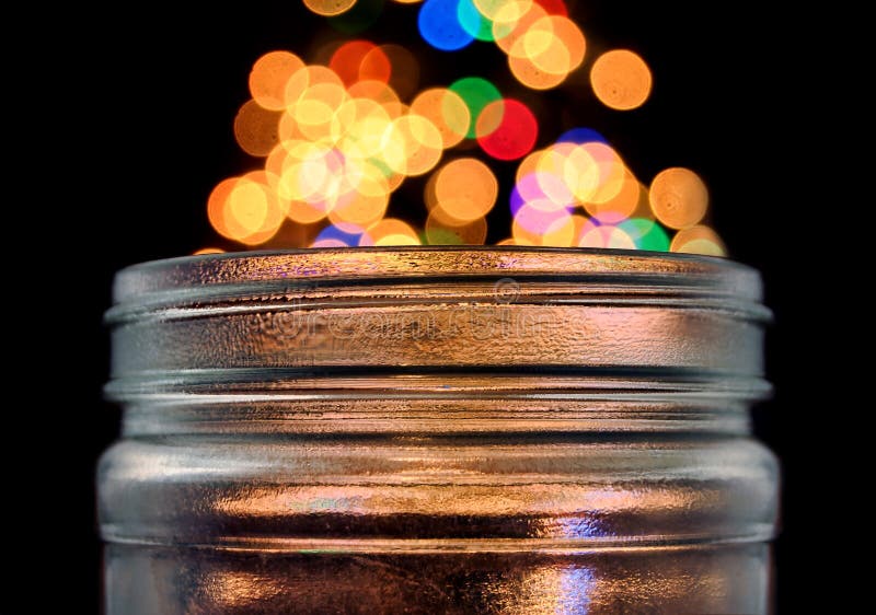 Clear glass jar with magical bokeh dots popping out. Isolated on black background. Clear glass jar with magical bokeh dots popping out. Isolated on black background