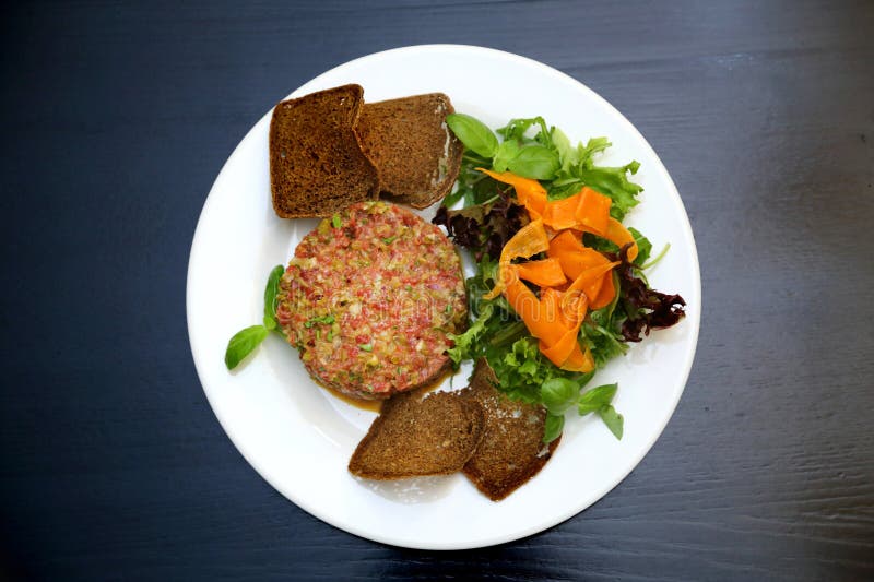 Tartar de carne cruda para gourmets. tartar de carne cruda con cubos de especias y hierbas. tartar de carne de vacuno con alcaparr foto de archivo libre de regalías