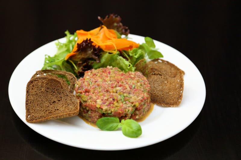 Tartar de carne cruda para gourmets. tartar de carne cruda con cubos de especias y hierbas. tartar de carne de vacuno con alcaparr fotos de archivo