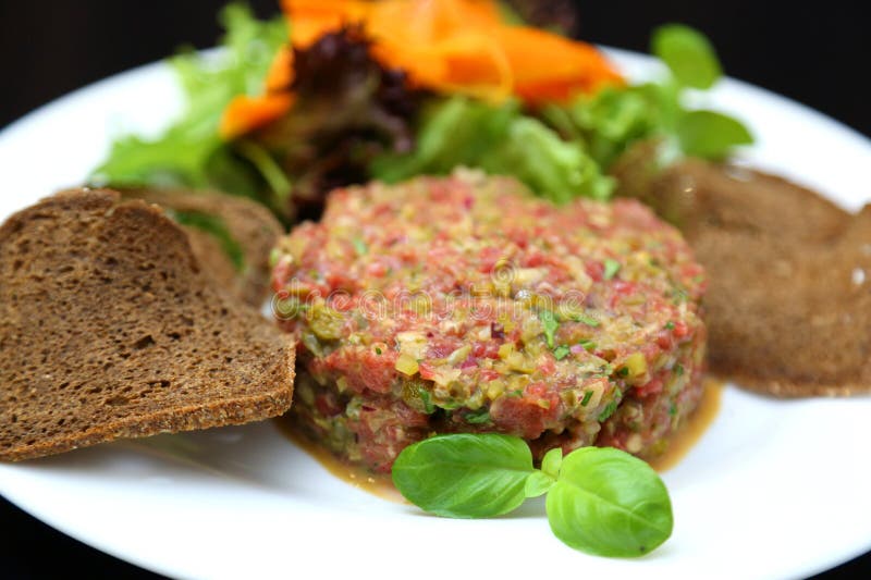 Tartar de carne cruda para gourmets. tartar de carne cruda con cubos de especias y hierbas. tartar de carne de vacuno con alcaparr imagen de archivo