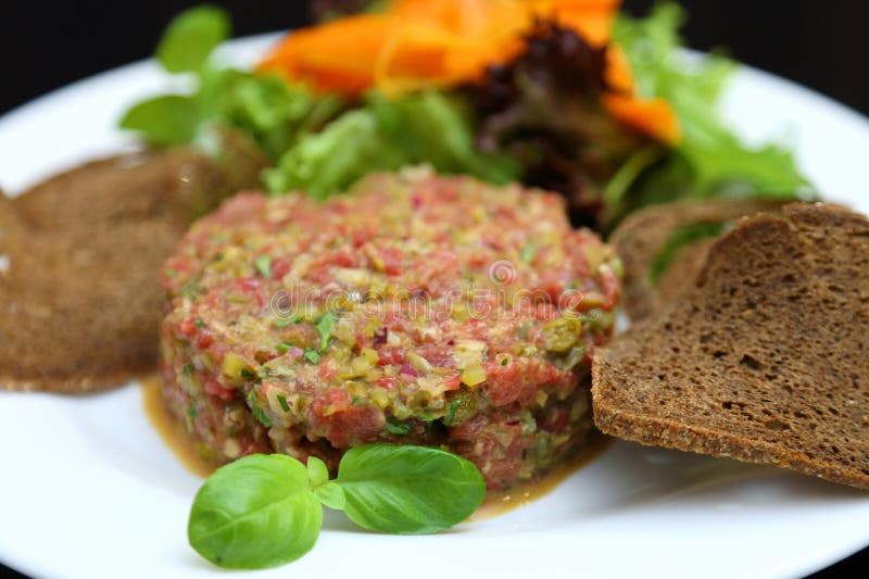 Tartar de carne cruda para gourmets. tartar de carne cruda con cubos de especias y hierbas. tartar de carne de vacuno con alcaparr fotografía de archivo