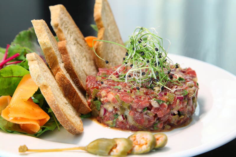 Tartar de carne cruda para gourmets. tartar de carne cruda con cubos de especias y hierbas. tartar de carne de vacuno con alcaparr fotografía de archivo libre de regalías