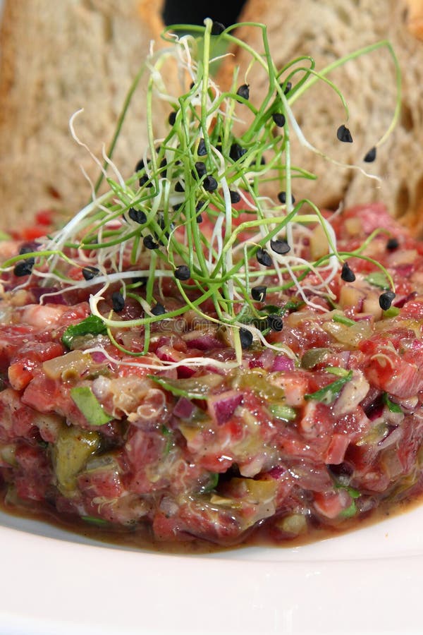 Tartar de carne cruda para gourmets. tartar de carne cruda con cubos de especias y hierbas. tartar de carne de vacuno con alcaparr foto de archivo libre de regalías