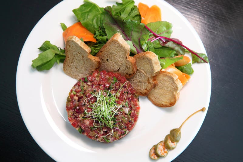 Tartar de carne cruda para gourmets. tartar de carne cruda con cubos de especias y hierbas. tartar de carne de vacuno con alcaparr imagenes de archivo