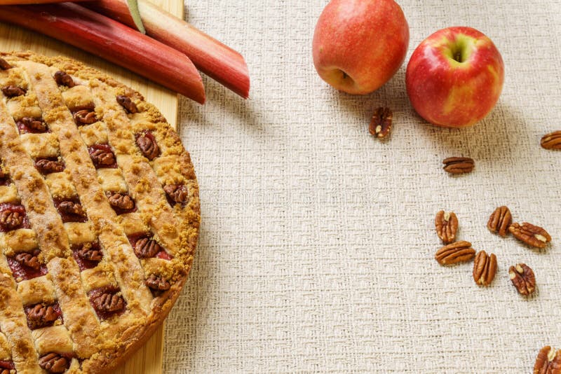 Tarte entier de pomme et de rhubarbe avec la noix de pécan sur un plateau noir sur une table photographie stock libre de droits Tarte entier de pomme et de rhubarbe avec la noix de pécan sur un plateau noir sur une table photographie stock libre de droits