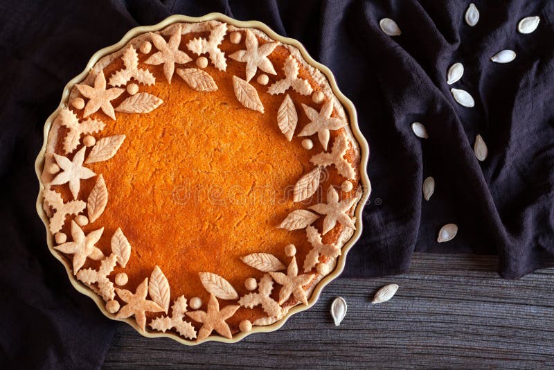 Delicious traditional thanksgiving pumpkin tart pie sweet organic dessert recipe with various decoration on top. Healthy nutrition vegan pastry. Dark cloth, vintage wooden table background. Rustic style. Delicious traditional thanksgiving pumpkin tart pie sweet organic dessert recipe with various decoration on top. Healthy nutrition vegan pastry. Dark cloth, vintage wooden table background. Rustic style.