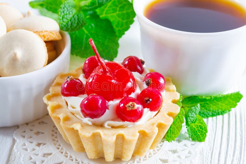 Tartlet delicioso con las bayas y queso cremoso fresco, una taza de té y pequeñas galletas fotografía de archivo Tartlet delicioso con las bayas y queso cremoso fresco, una taza de té y pequeñas galletas fotografía de archivo