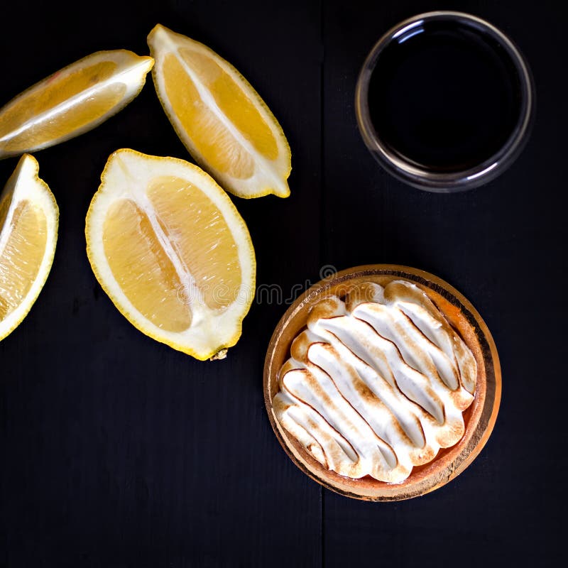 Tartlet with meringue and lemon on a black background isolated close-up. Tartlet with meringue and lemon on a black background isolated close-up