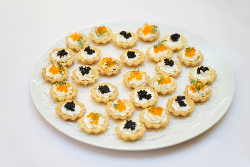 Tartlets con el caviar negro y rojo en una placa blanca fotografía de archivo libre de regalías Tartlets con el caviar negro y rojo en una placa blanca fotografía de archivo libre de regalías