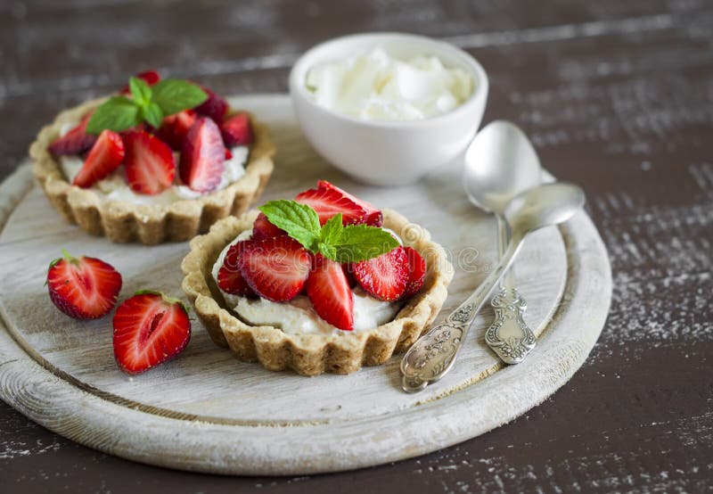 Tartlets with cream and strawberries, decorated with mint leaves