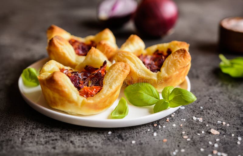 Tartlets de la cebolla roja y del tomate secado al sol mini foto de archivo libre de regalías Tartlets de la cebolla roja y del tomate secado al sol mini foto de archivo libre de regalías