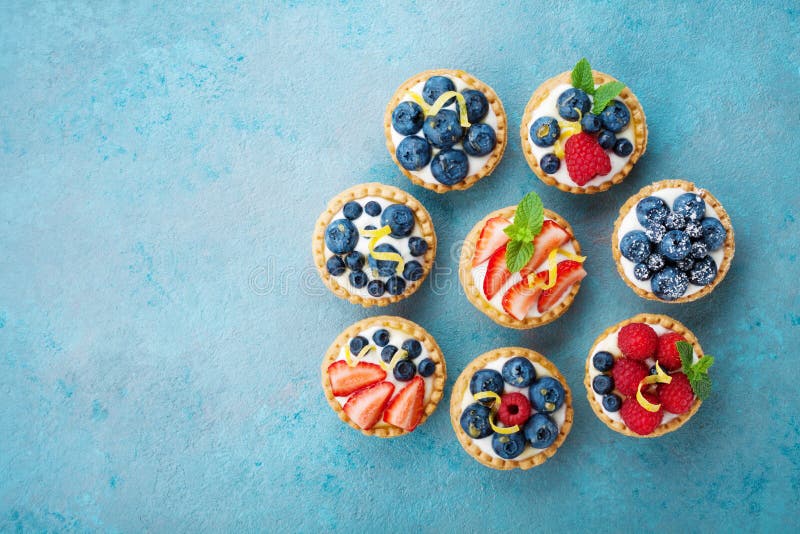 Tartlets lub tort z kremowym serem i jagodą na turkusu stole od above Wyśmienicie kolorowy ciasto deser zdjęcie royalty free Tartlets lub tort z kremowym serem i jagodą na turkusu stole od above Wyśmienicie kolorowy ciasto deser zdjęcie royalty free