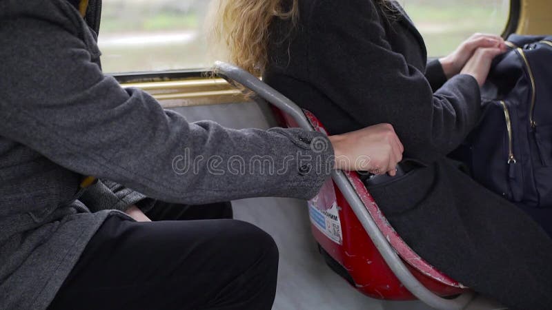 Taschendieb, der Telefon von einer Frau ` s Tasche in der Tram oder im Bus stiehlt