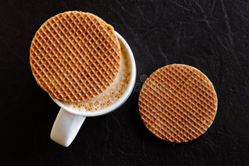 Tasse blanche avec du café écumeux laiteux et un biscuit rond de gaufre dessus photographie stock Tasse blanche avec du café écumeux laiteux et un biscuit rond de gaufre dessus photographie stock