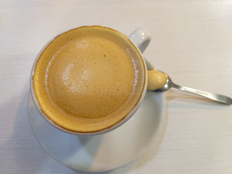 tasse de café blanche avec du lait une cuillère à café métallique sur une soucoupe blanche sur une table blanche photographie stock libre de droits tasse de café blanche avec du lait une cuillère à café métallique sur une soucoupe blanche sur une table blanche photographie stock libre de droits