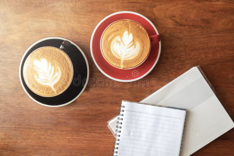 Tasse de café chaud avec l'art de latte dans la forme de feuille et le livre vide Vue sup?rieure avec l'espace de copie sur la ta image stock Tasse de café chaud avec l'art de latte dans la forme de feuille et le livre vide Vue sup?rieure avec l'espace de copie sur la ta image stock
