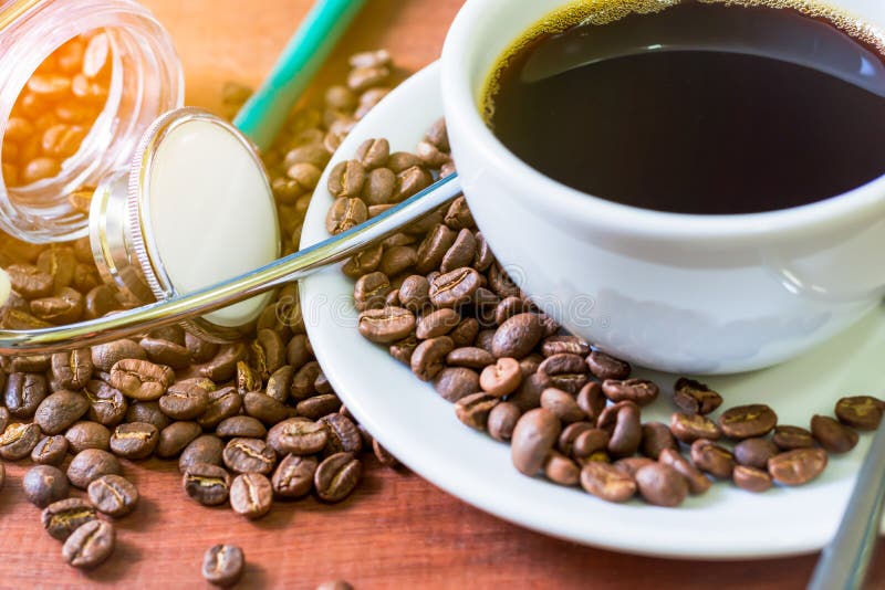 Tasse de café foncé avec les grains de café et le stéthoscope sur le fond en bois Concept de santé de qui comme la boisson un caf image libre de droits Tasse de café foncé avec les grains de café et le stéthoscope sur le fond en bois Concept de santé de qui comme la boisson un caf image libre de droits