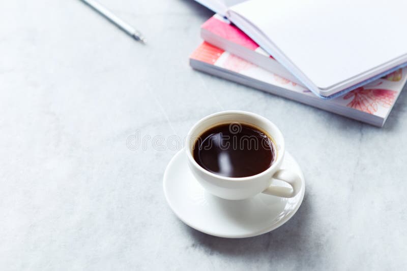 Tasse de café noir sur le fond de marbre gris ; livres et carnet à l'arrière-plan