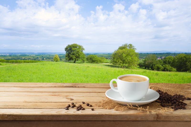 Tasse de café sur la table en bois au-dessus du beau fond de paysage photo libre de droits Tasse de café sur la table en bois au-dessus du beau fond de paysage photo libre de droits