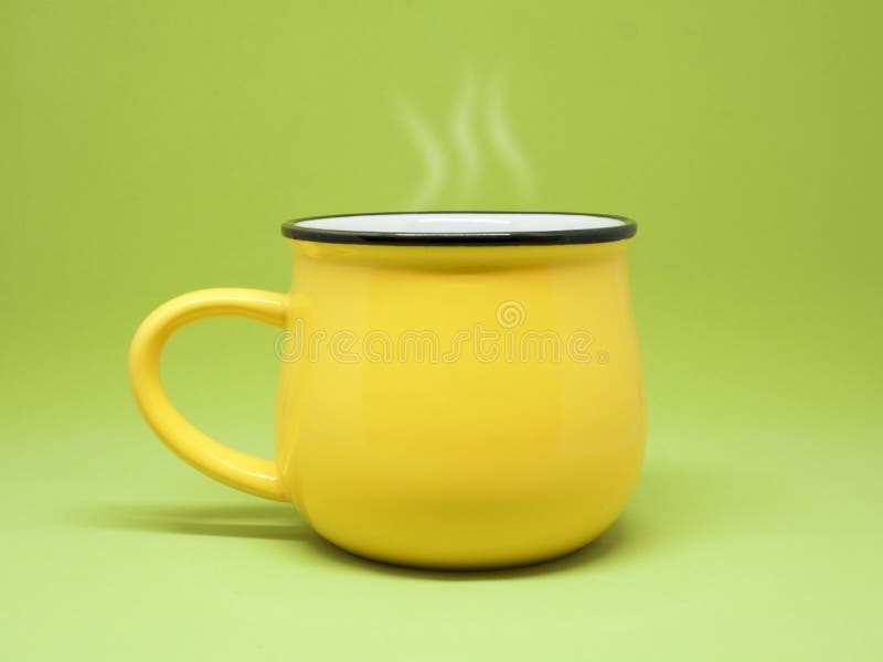 Tasse jaune d'isolement sur un fond vert, vapeur se levant images libres de droits Tasse jaune d'isolement sur un fond vert, vapeur se levant images libres de droits