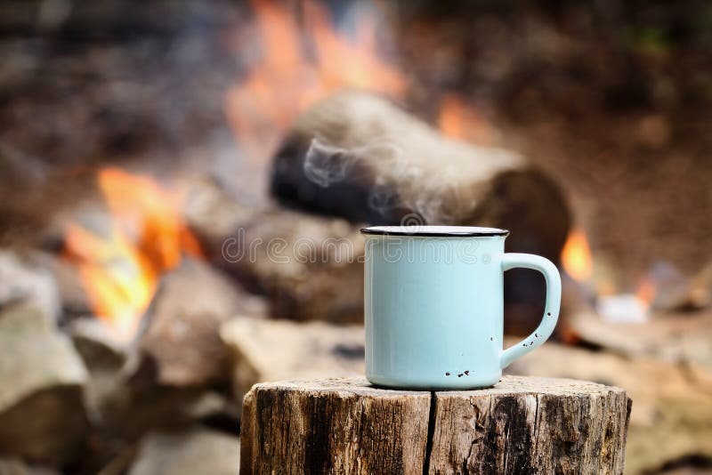 Tasse Kaffee durch ein Lagerfeuer