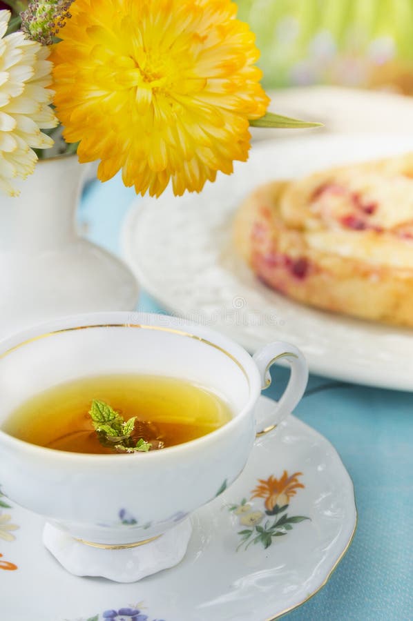 Tasse Tee mit Minze auf Hintergrund des Kuchens und der Blumen stockbild Tasse Tee mit Minze auf Hintergrund des Kuchens und der Blumen stockbild