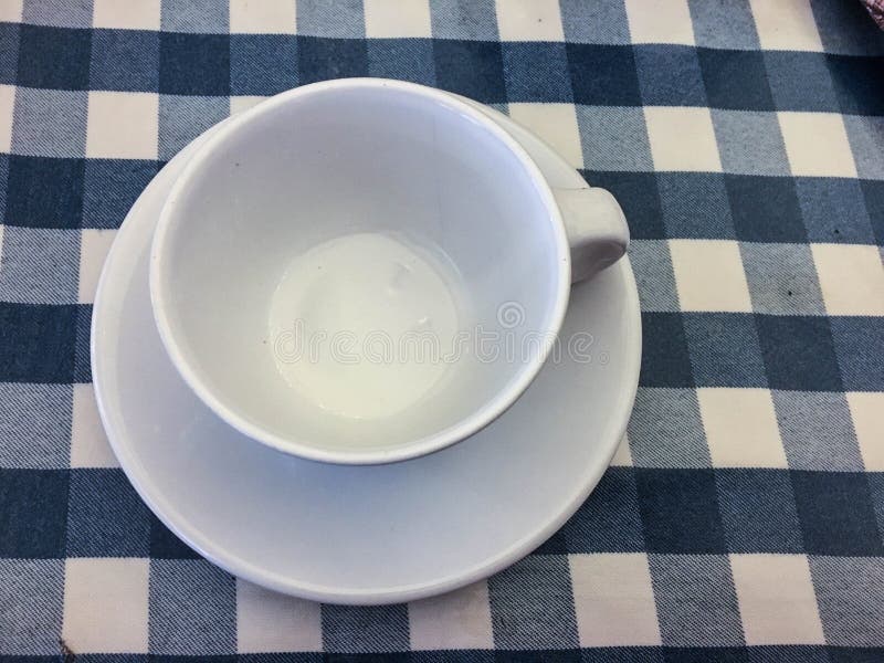Tasse vide blanche et tablecloath bleu image libre de droits Tasse vide blanche et tablecloath bleu image libre de droits