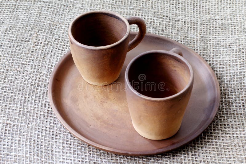 Tasses de café d'argile et plat en céramique fait main sur un fond de fabrication domestique approximatif de jute photo libre de droits Tasses de café d'argile et plat en céramique fait main sur un fond de fabrication domestique approximatif de jute photo libre de droits