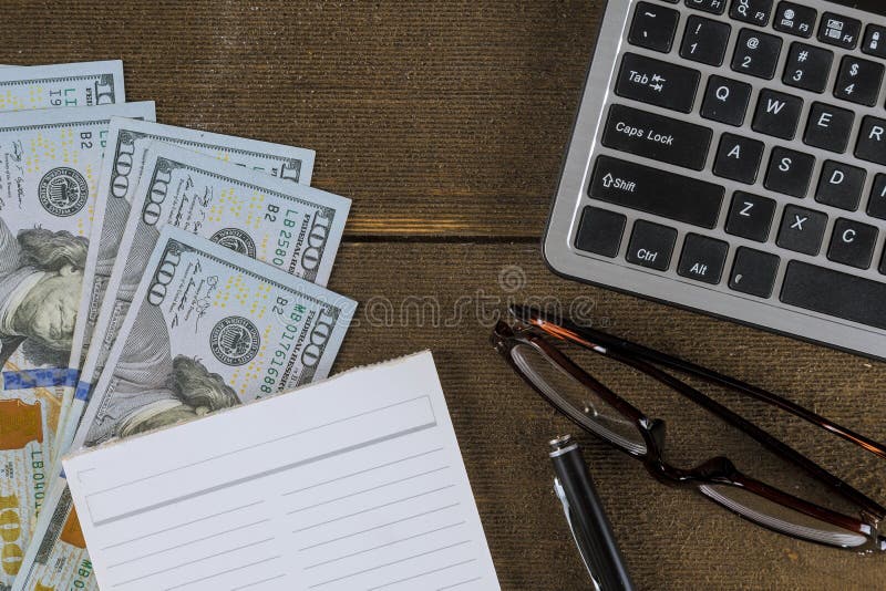 Tastatură de calculator cu bani în dolari pe stiloul și pe sticla din lemn stock photo