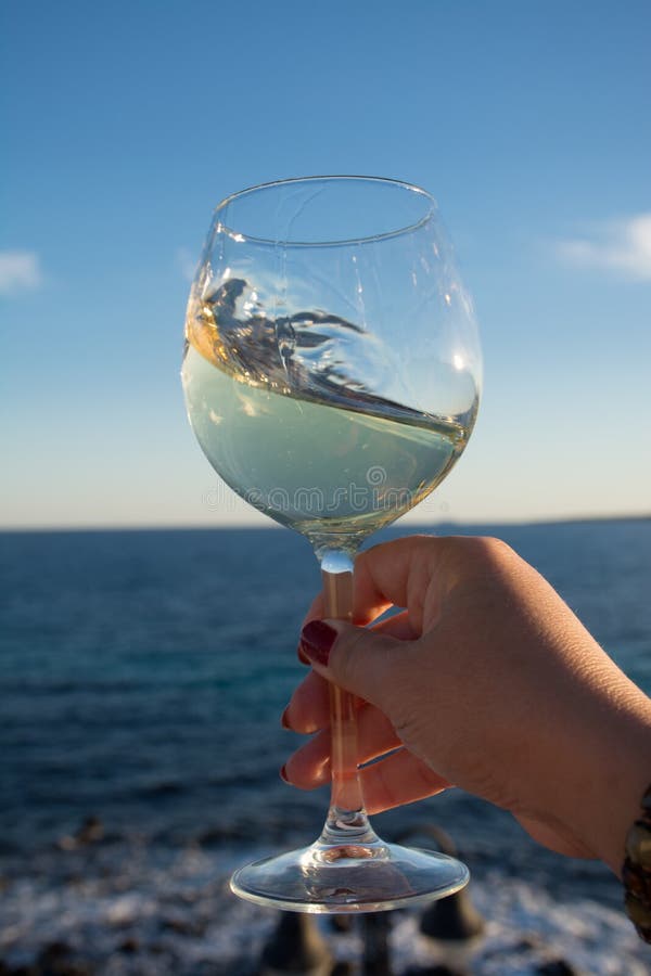 Tasting of glass of cold white wine on outdoor terrace with sea royalty free stock images