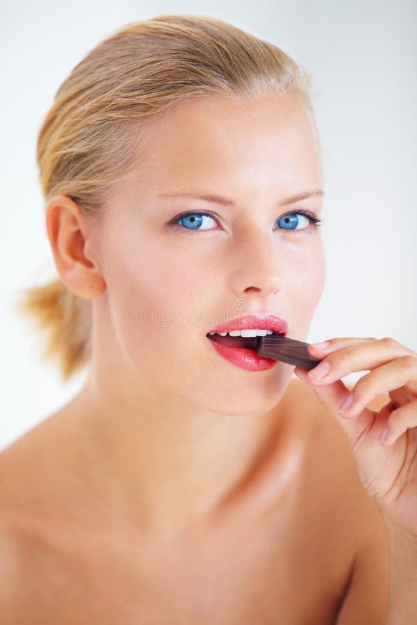 Tasting the sweetness. Beautiful young woman enjoying a delicious piece of chocolate.