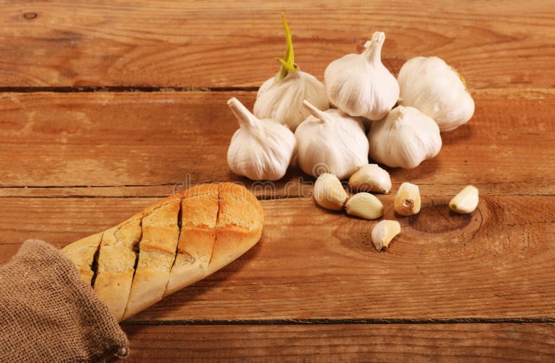 Tasty Bread with Garlic. Sliced Garlic, Garlic Clove, Garlic Bulb, on Kitchen Wooden Table Stock