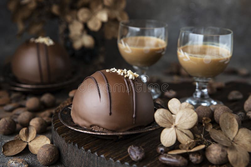 Vanilla mousse cake with dark chocolate, sweet desser on table with glass of liquor . Dessert holiday table. Vanilla mousse cake with dark chocolate, sweet desser on table with glass of liquor . Dessert holiday table