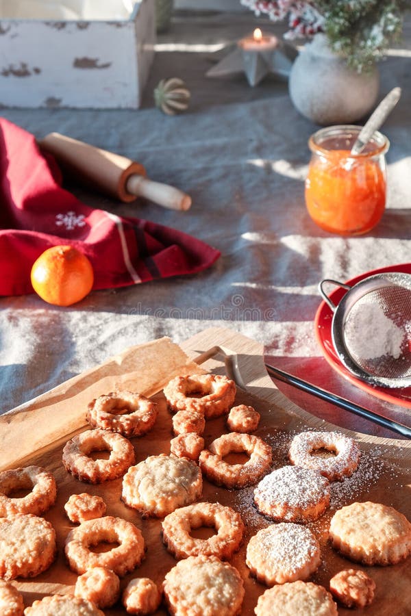 Yummy Linzer cookies filled with orange jam on cooling rack and vintage metal plate. Xmas stollen on table with natural