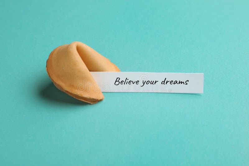 Tasty fortune cookie with prediction Believe your dreams on cyan background royalty free stock images