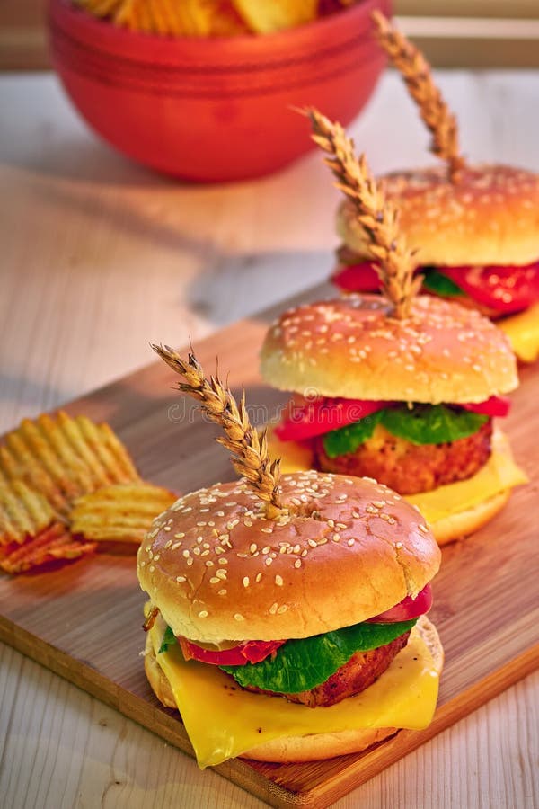 Tasty grilled beef burgers with lettuce, tomato, cheese and mayonnaise on rustic wooden board. Home made gamburgers. Fast food. royalty free stock image Tasty grilled beef burgers with lettuce, tomato, cheese and mayonnaise on rustic wooden board. Home made gamburgers. Fast food. royalty free stock image