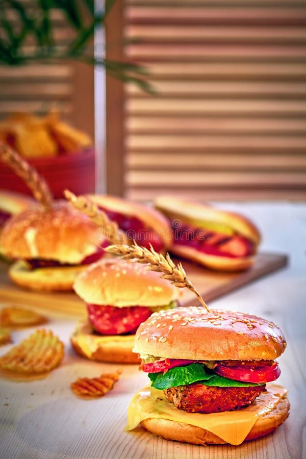 Tasty grilled beef burgers with lettuce, tomato, cheese and mayonnaise on rustic wooden table. Home made gamburgers, copy space. stock photography Tasty grilled beef burgers with lettuce, tomato, cheese and mayonnaise on rustic wooden table. Home made gamburgers, copy space. stock photography