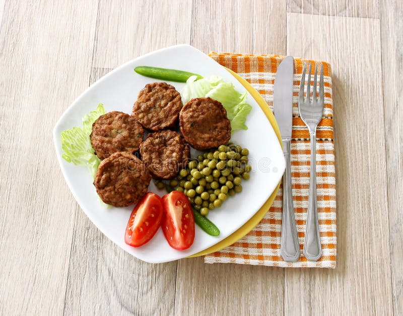 Tasty meatballs, green peas and tomatoes on plate