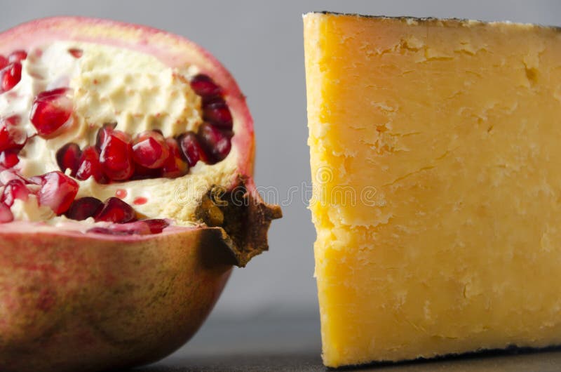 Tasty pomegranate and gouda cheese against grey wall.Closeup view.Fruits and dairy products stock photography Tasty pomegranate and gouda cheese against grey wall.Closeup view.Fruits and dairy products stock photography