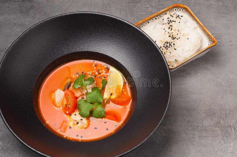 Tom Yam with Seafood in a Dark Dish and Rice Stock Image - Image of