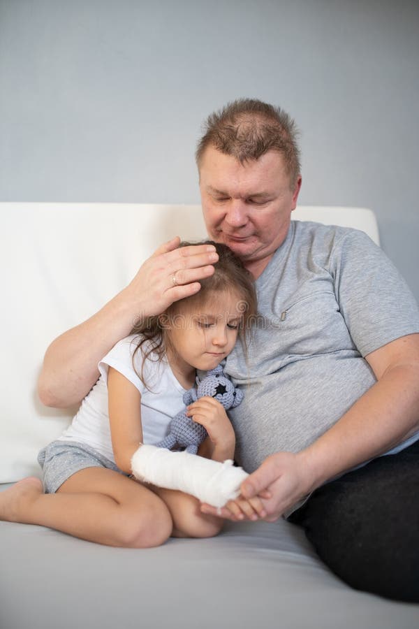 Tata lituje się, że córka gips na ramieniu fotografia stock