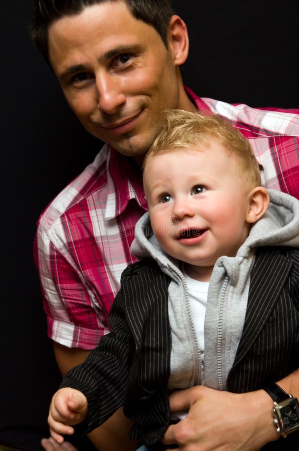 Happy young dad or father with baby son, black studio background. Happy young dad or father with baby son, black studio background.