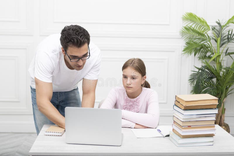 Tata și fiica studiind împreună online acasă. Explicând lecția și ascultându-l cu atenție stock images