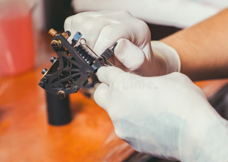 Tatoegeringskunstenaar in rubber witte handschoenen die klaar om een tatoegering te doen worden royalty-vrije stock fotografie Tatoegeringskunstenaar in rubber witte handschoenen die klaar om een tatoegering te doen worden royalty-vrije stock fotografie