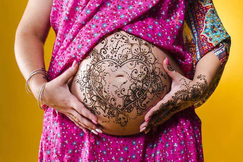 A color photo of a henna tatoo on a woman's pregnant belly, on yellow background. A color photo of a henna tatoo on a woman's pregnant belly, on yellow background.
