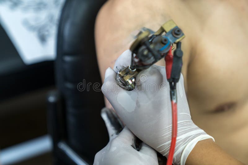 Tattoo Artist in White Gloves Making a Tattoo on Man Arm Stock Image