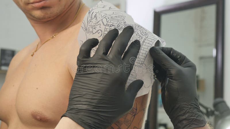 Tatueringkonstnären applicerar skissa på handen för man` s