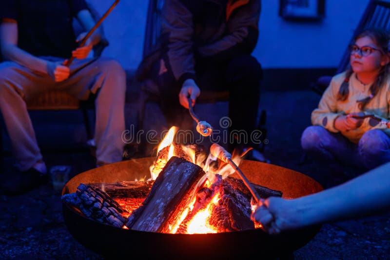Tată fetiță școală și adolescent băiat stau de tabără foc și copt stickbread. Familie împreună. Legătura dintre tată și copii stock images