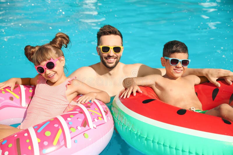Tată și copii cu inele gonflabile în piscină. vacanță de familie royalty free stock photography